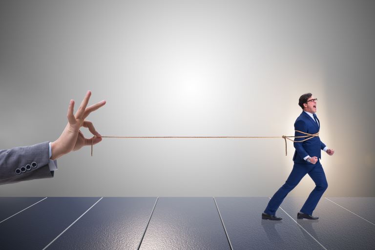 Man ties up in ropes being pulled by enlarge hand of business person | Improve employee retention